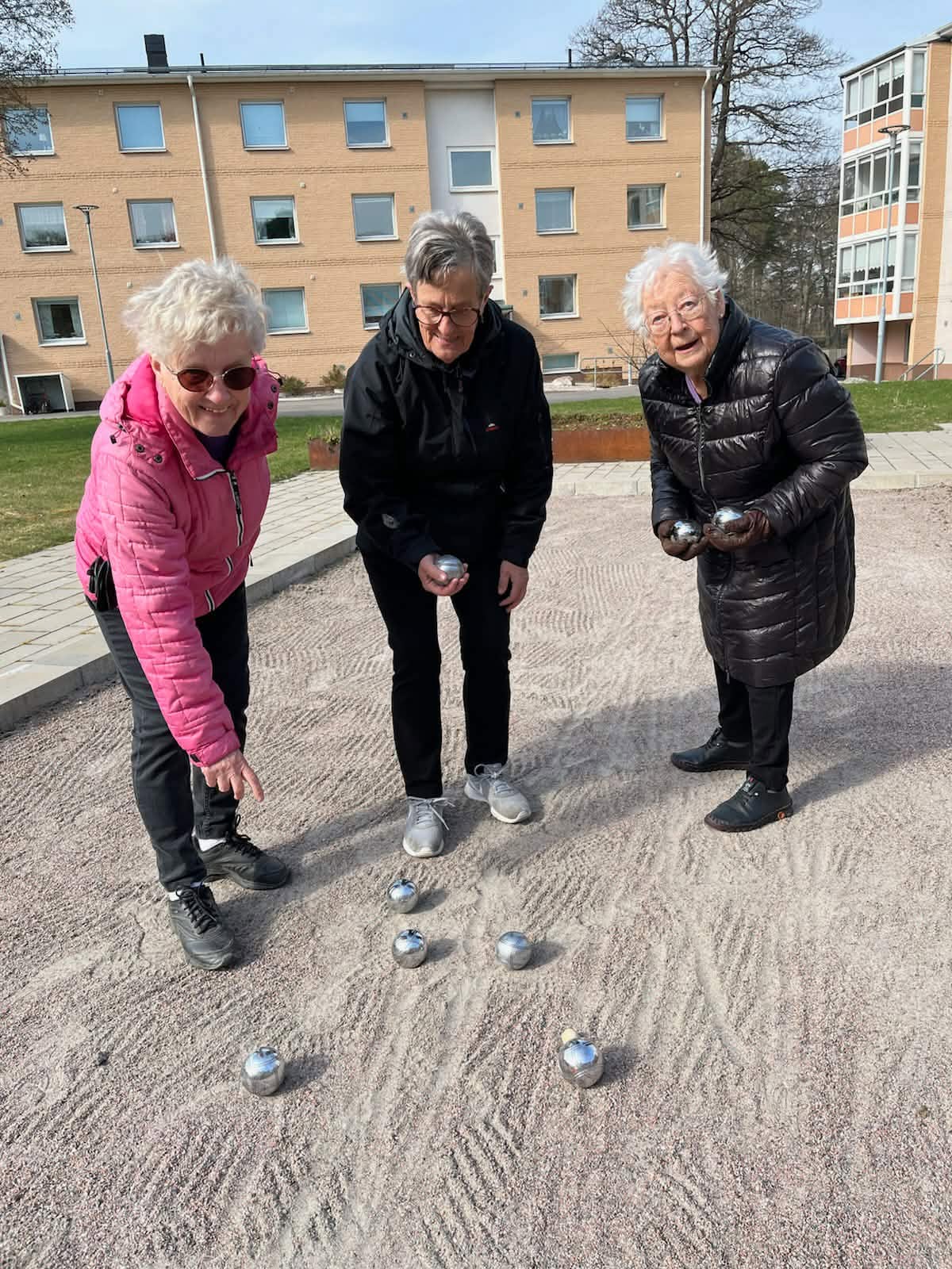 Tre medlemmar spelar boule på grusplanen